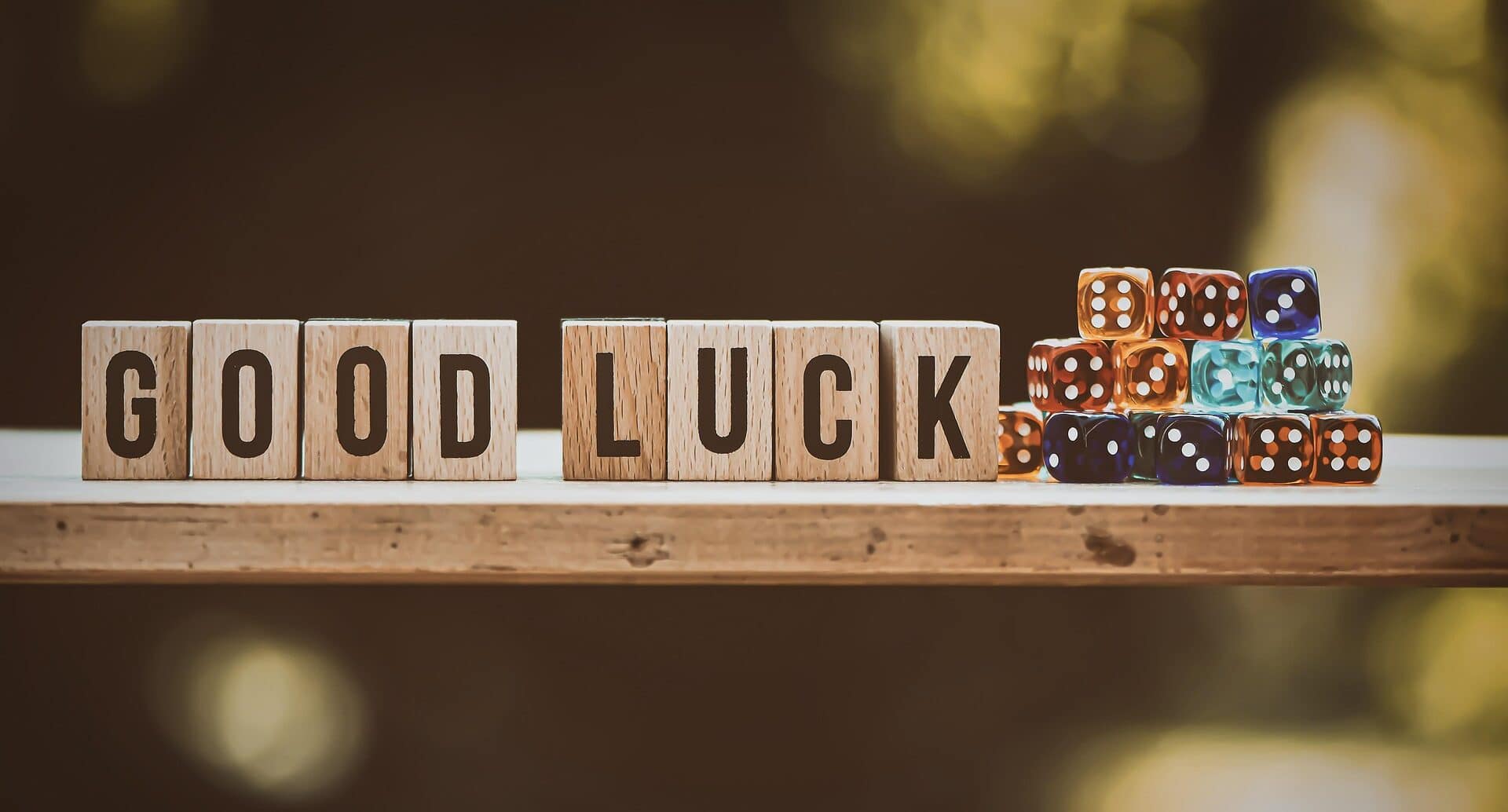 A shelf containing wooden blocks with letters on the wide, spelling "good luck". Beside this is a pile of D6 dice
