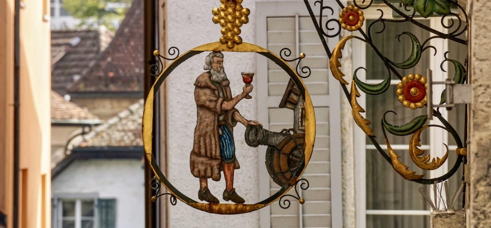 A metal pub sign depicting a main holding a glass of wine